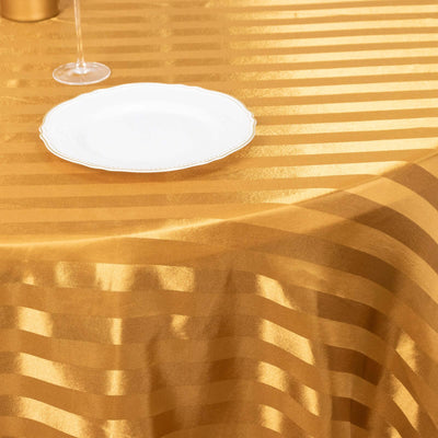 Gold striped tablecloth with a white plate, elegant dining setting.