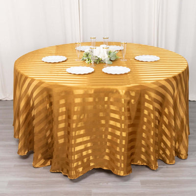 Round gold striped tablecloth on a dining table with plates and decor.