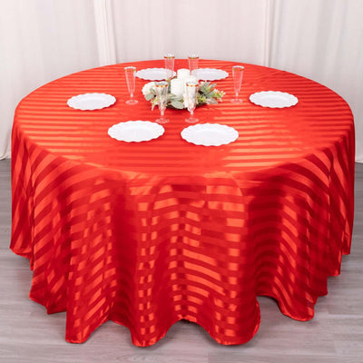 Red striped tablecloth draped over a round table set for dinner.