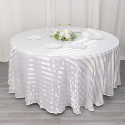 Round table covered with a white striped tablecloth and decorative plates.