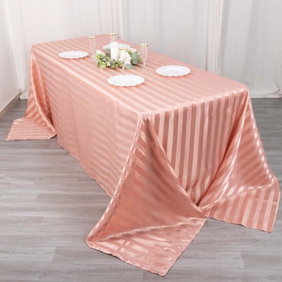 Elegant blush pink striped tablecloth draped over a dining table.