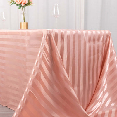 Pink striped tablecloth draped elegantly over a table with glasses and flowers.