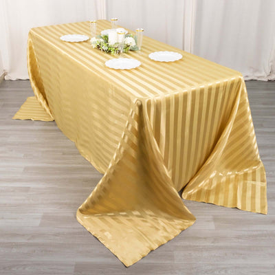 Gold striped tablecloth draped elegantly over a table with decorative candles and plates.