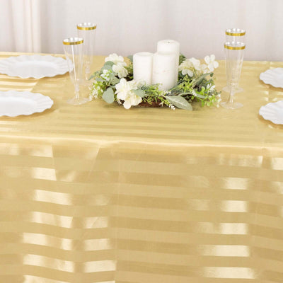 Gold striped tablecloth with floral centerpiece and elegant glassware.
