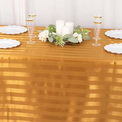Elegant gold tablecloth with white plates, floral centerpiece, and glassware.