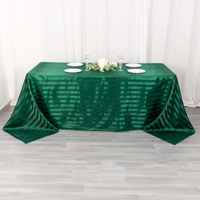 Green striped tablecloth draped over a table with plates and candles.