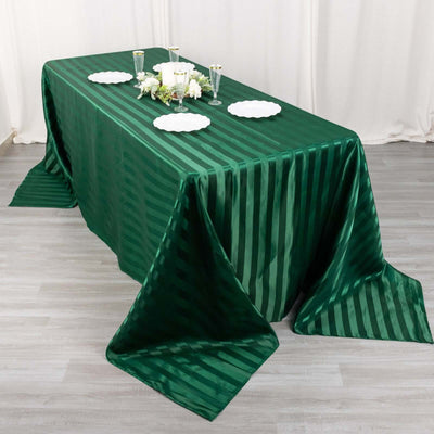Elegant green striped tablecloth draped on a table with decorative accessories.