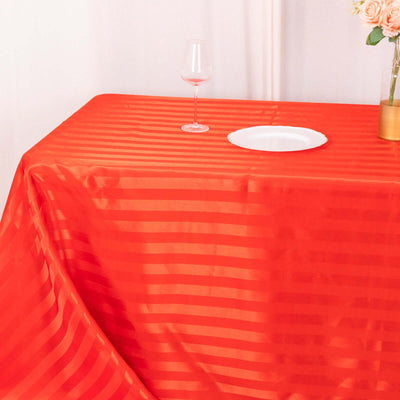 Red striped tablecloth on a table with a glass and plate set.