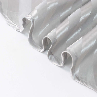 Silver satin fabric with elegant wave pattern and smooth texture.