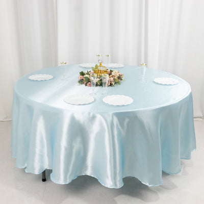 Round table adorned with a light blue satin tablecloth and decorative centerpieces.