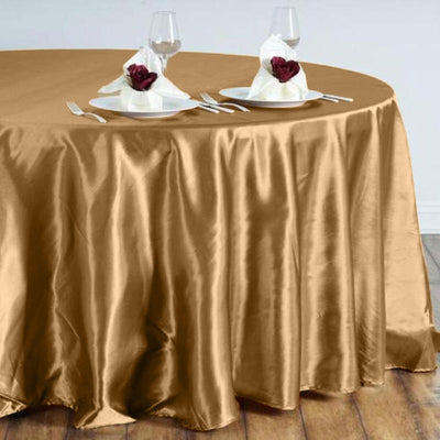 Gold satin round tablecloth draped over a table set for dining.
