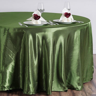 Elegant green tablecloth on a round table set with plates and napkins.