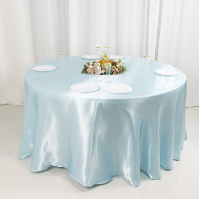 Round table dressed in a light blue satin tablecloth with elegant decorations.