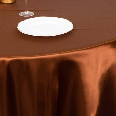 Elegant brown tablecloth with a white plate and glass on a dining table.