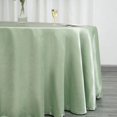 Elegant green satin tablecloth draping over a table with a glass and plate.