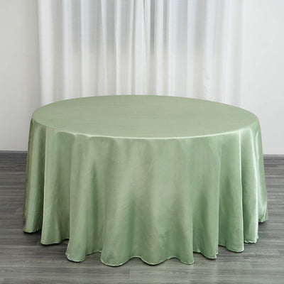 Round green tablecloth on a wooden floor with curtains in the background.