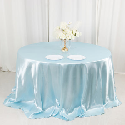 Round table covered with a light blue satin tablecloth and floral centerpiece.