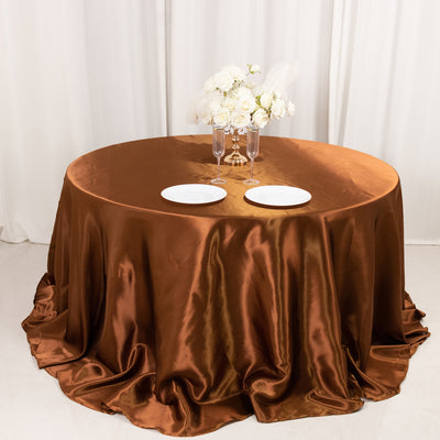 Elegant round table with brown satin tablecloth and floral centerpiece.