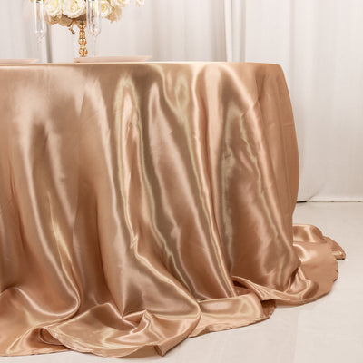 Satin tablecloth in soft gold draping elegantly over a round table.