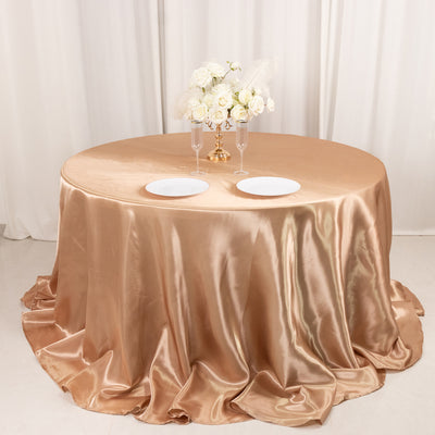 Elegant round table with champagne satin tablecloth and floral centerpiece.