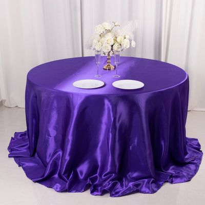 Purple satin tablecloth with white plates and floral centerpiece.