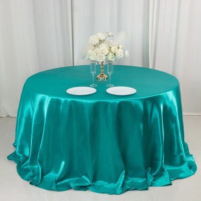 Teal satin tablecloth with white plates and floral centerpiece