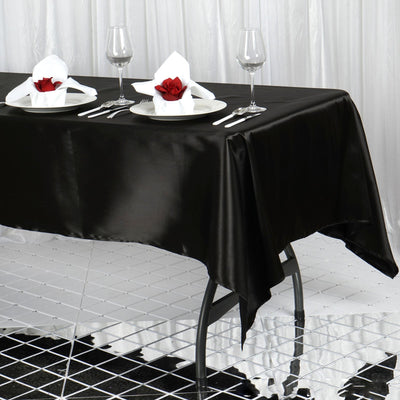 Elegant black tablecloth set with plates, wine glasses, and rose centerpieces.