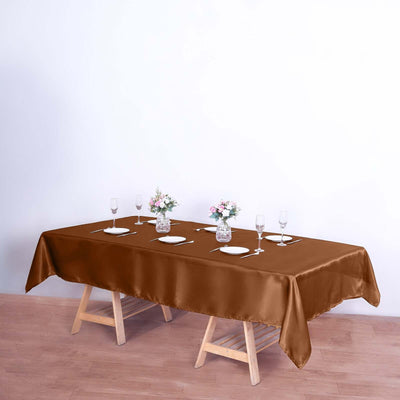 Brown satin tablecloth draped over a wooden table with decorative centerpieces.