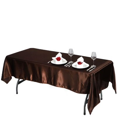 Brown satin tablecloth draped over a dining table with set plates and glassware.