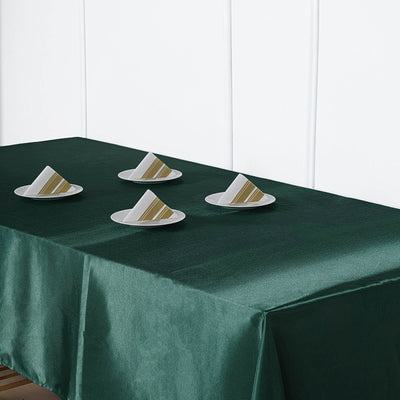 Green tablecloth with plates and folded napkins arranged on top.