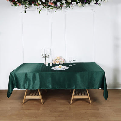 Green tablecloth draped over a wooden table with decorative flowers and candles.