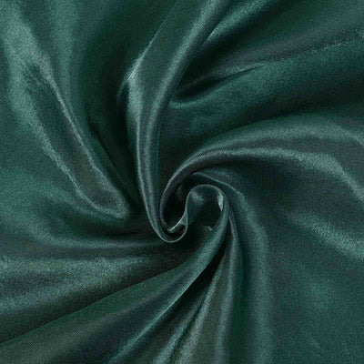 Deep green satin fabric swirl texture close-up.