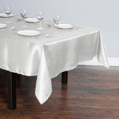 Elegant satin tablecloth draping over a wooden table, set for dining.