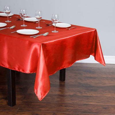 Red satin tablecloth on a dining table set for a meal.