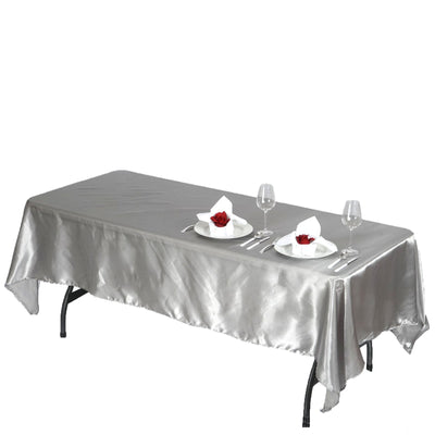 Silver tablecloth draped over a table set for two with plates and wine glasses.