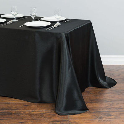 Elegant black tablecloth draped over a dining table with plates and glassware.