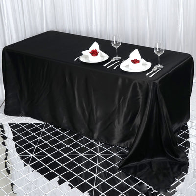 Elegant black tablecloth set for dining with plates and glasses.