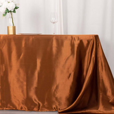 Elegant brown satin tablecloth draped over a table with a vase and wine glass.