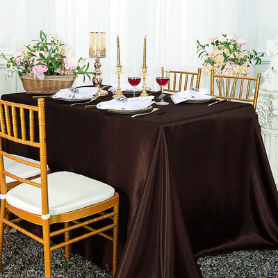 Elegant brown tablecloth draped over a dining table set with candles and wine glasses.