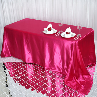 Pink satin tablecloth with elegant table setting and reflections.