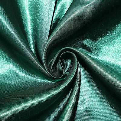 Shiny emerald green fabric with a smooth texture in a swirling pattern.
