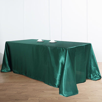 Green satin tablecloth draped over a table with decorative items on top.