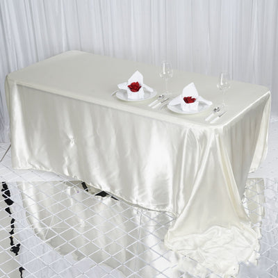 Elegant satin tablecloth set for a dining table with decorative napkins and glasses.