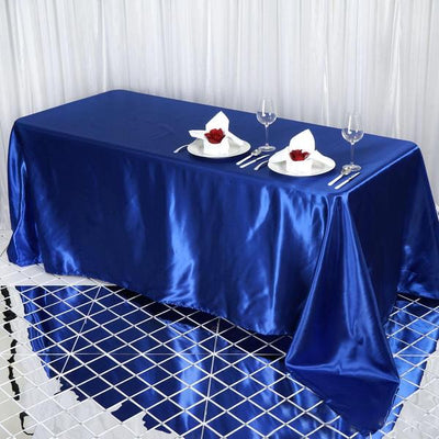 Elegant blue satin tablecloth set for dining, complete with plates and cutlery.