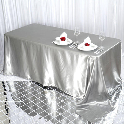 Silver satin tablecloth elegantly draped over a dining table setting.