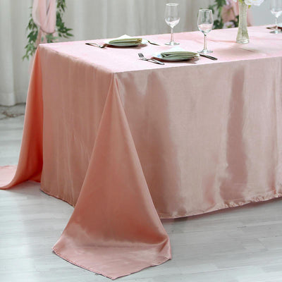 Elegant pink satin tablecloth drapes gracefully over a table setting.