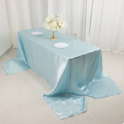 Elegant light blue satin tablecloth draped on a table with floral centerpiece.
