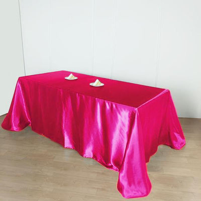Pink satin tablecloth draped over a table with decorative items on top.