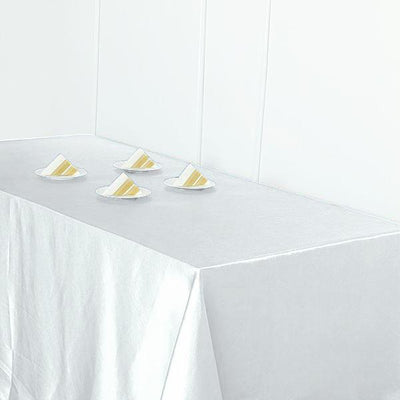 Four slices of cake on white plates on a white tablecloth.