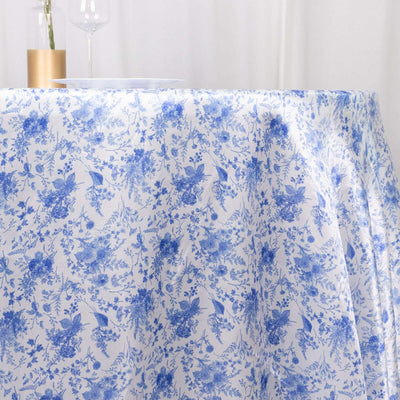 Blue floral tablecloth draped over a table with a glass and plate.